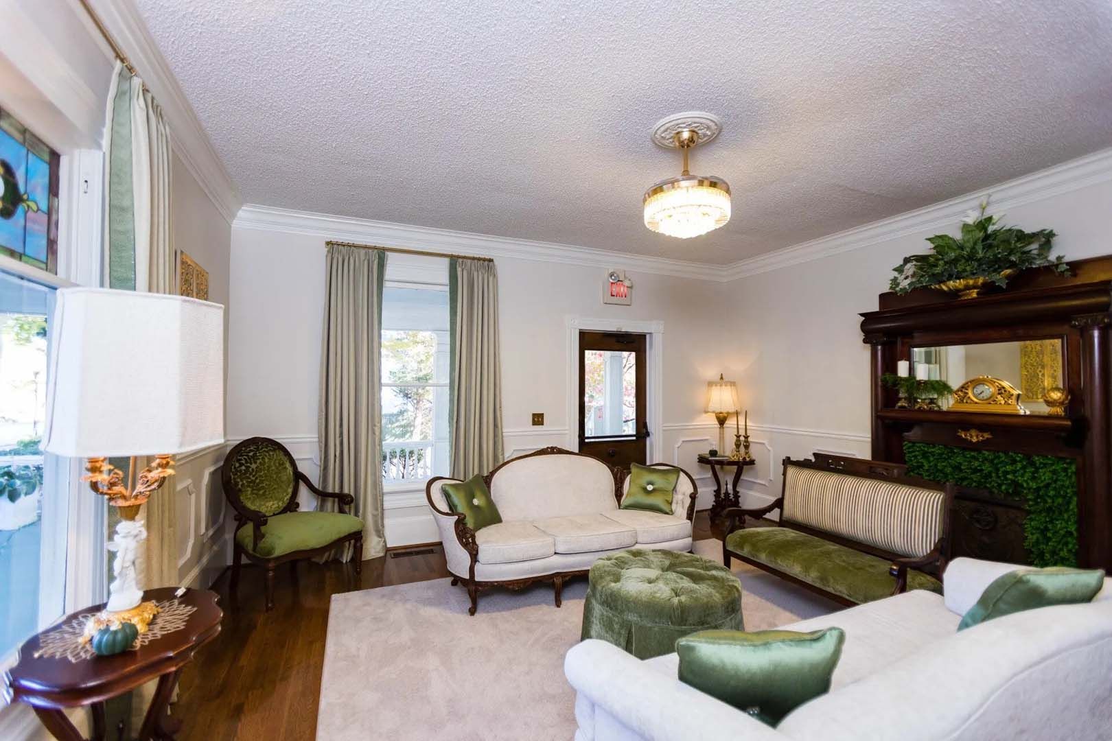 Elegant living room with white sofas, green accents, and antique furniture.