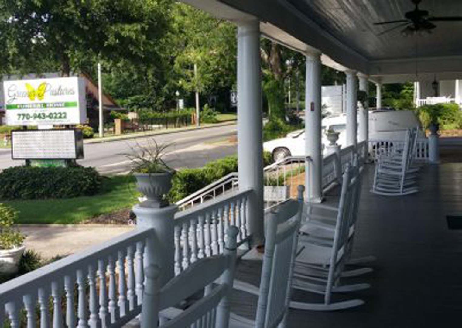 White porch with rocking chairs. A sign for 