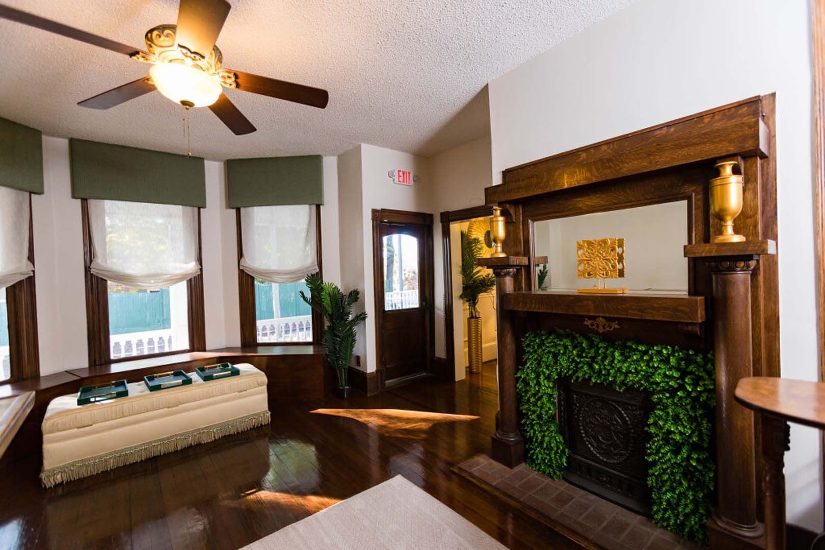 Living room with dark wood floors and trim, fireplace with greenery, and a bay window.