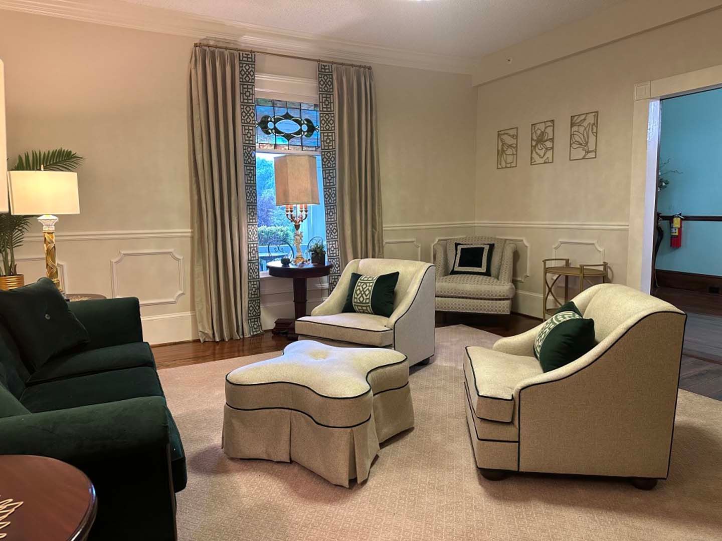 Living room with green sofa, beige armchairs, and patterned curtains.