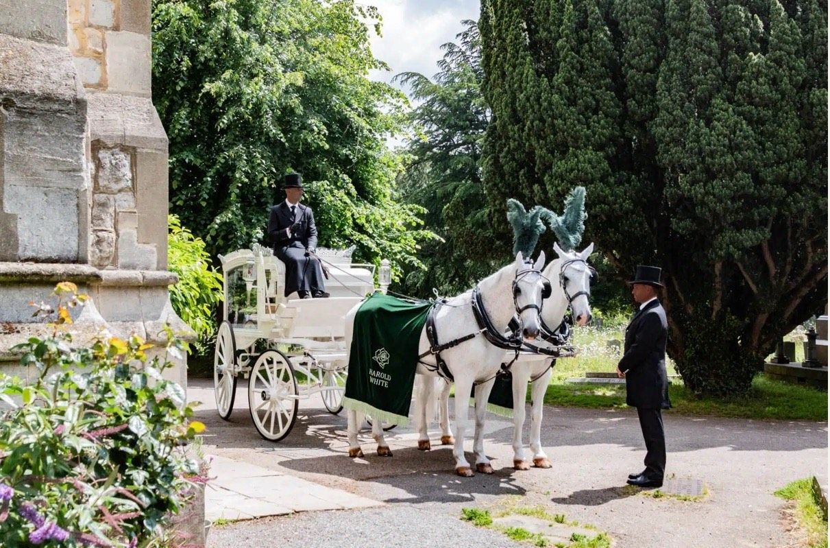A porch with white rocking chairs. Sign for Green Pastures business on left. Road visible.