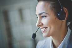 Woman wearing headset, smiling. Close-up in office.