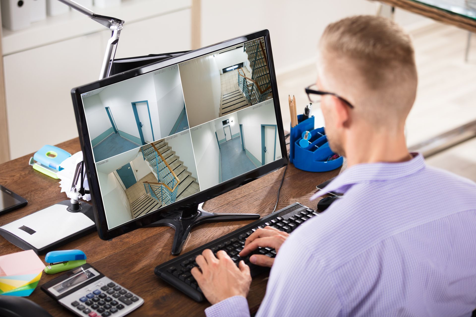 A man sits at a desk, viewing multiple images on a computer screen related to network video recordin