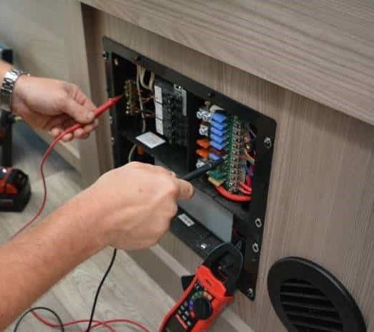 A person is using a multimeter to test a circuit board