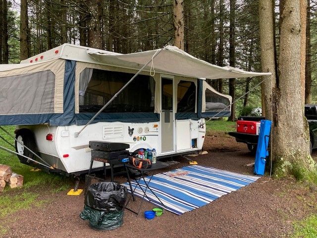 A camper is parked in the middle of a forest.