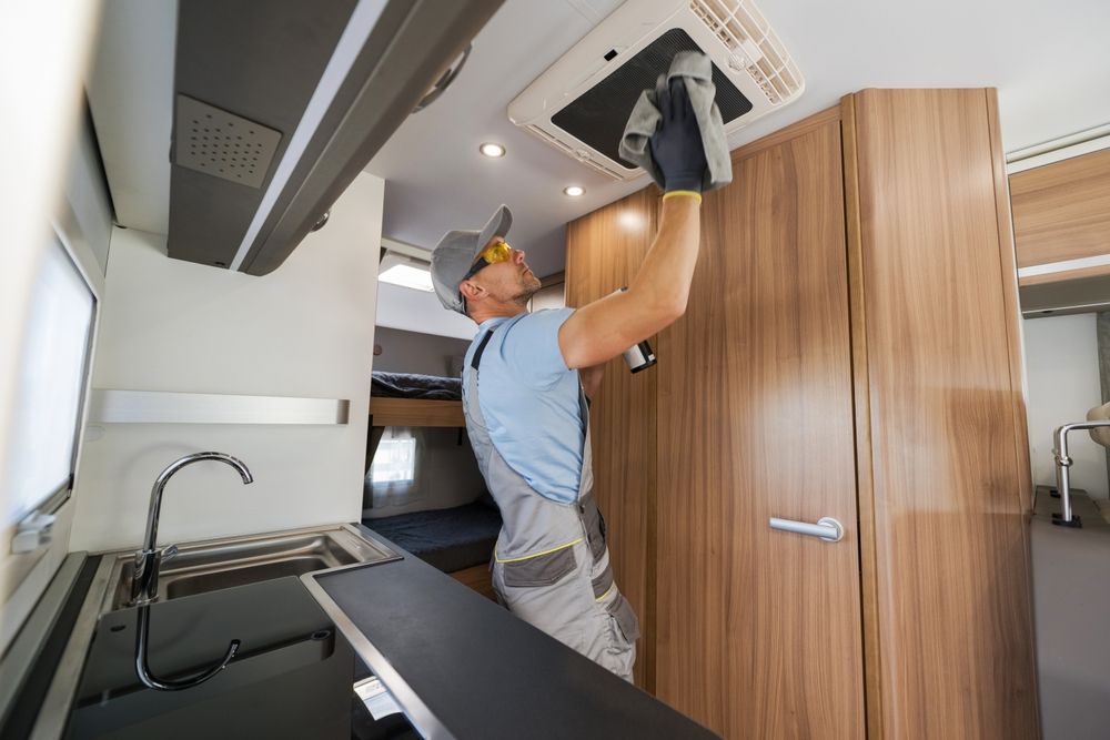 A man is working on the ceiling of a camper van.