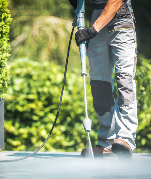 A man is using a high pressure washer to clean a sidewalk.