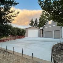 Concrete driveway in front of a house, with a cloudy sky in the background.