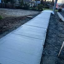 Freshly poured concrete sidewalk, slightly angled, in an outdoor setting.