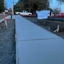 Newly poured concrete sidewalk with a white pickup truck in the background.