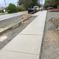 Newly constructed sidewalk alongside a street with a truck parked on the road.