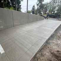Concrete sidewalk with a ramp and retaining wall.