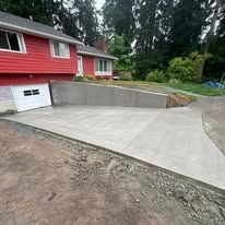 Concrete driveway in front of a red house with a wall.