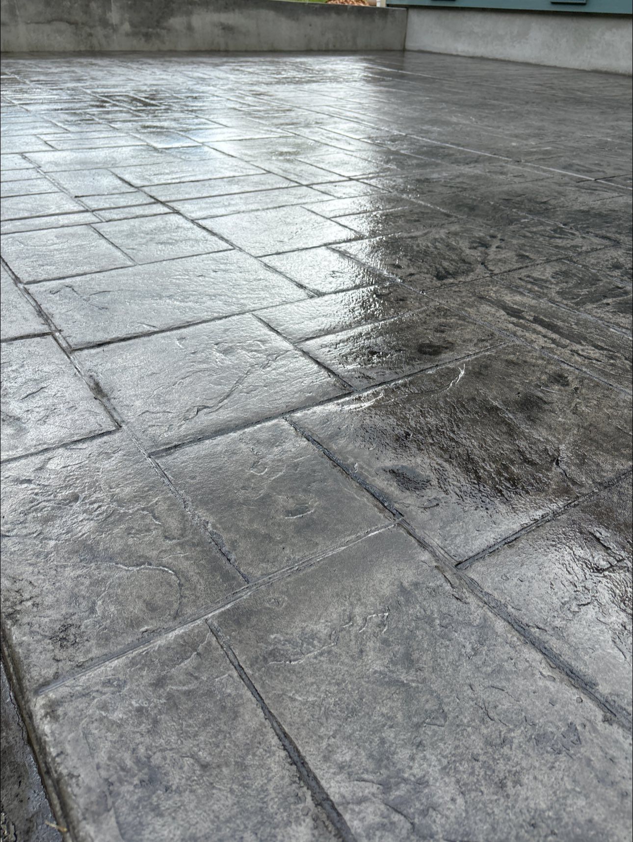 Gray, stamped concrete patio with wet, brick-like pattern.