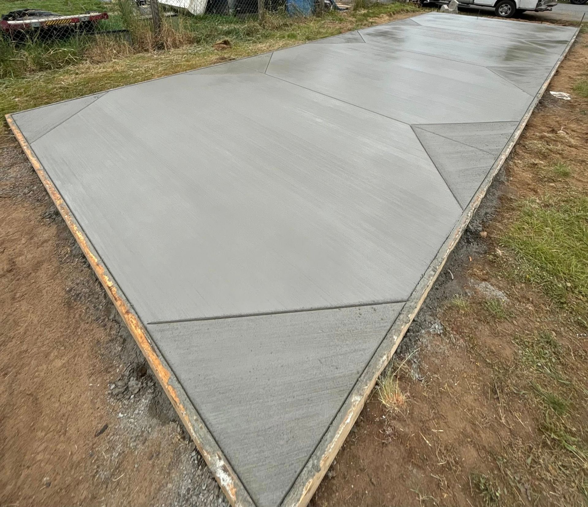 Newly poured concrete driveway with wooden border, outdoors.