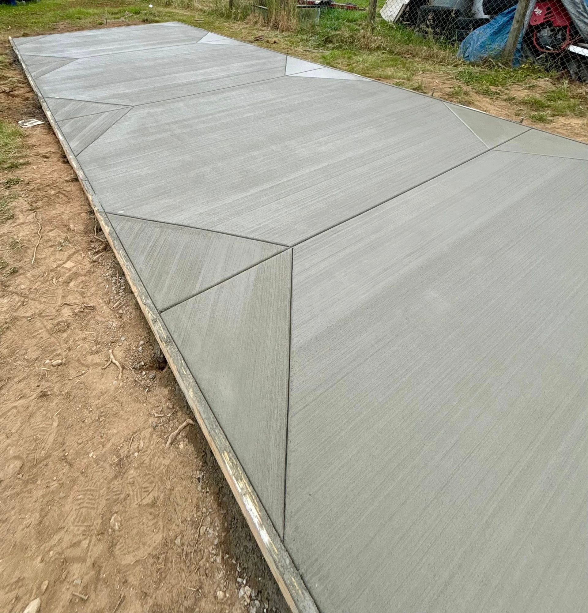 Newly poured concrete walkway with angled sections and brushed finish. Outdoor setting.