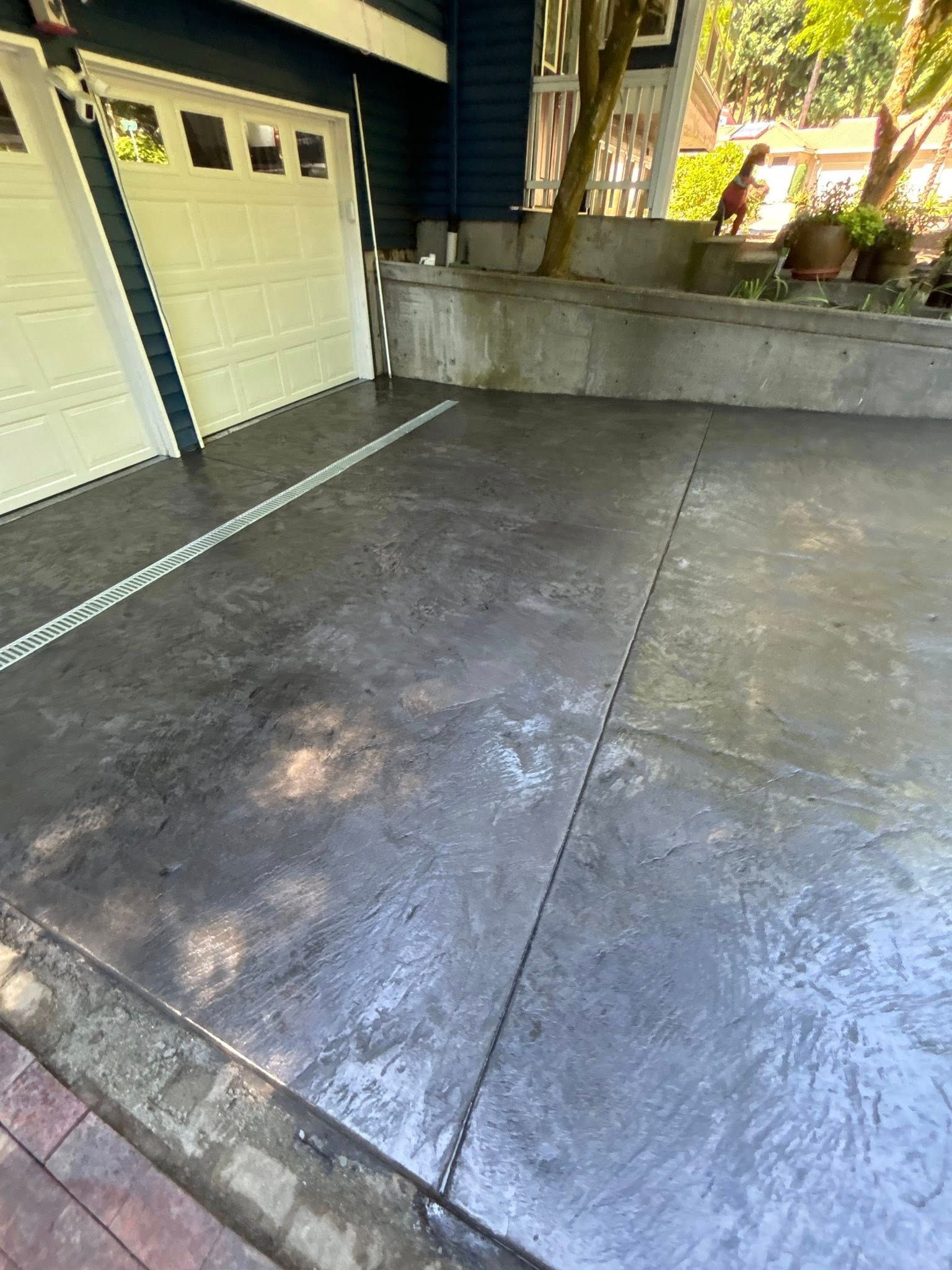 Gray stamped concrete driveway with garage door in background.