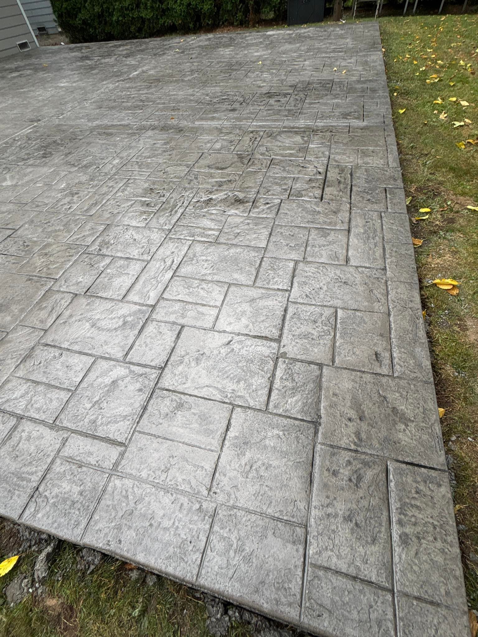 Grey patterned concrete patio next to a grassy area.
