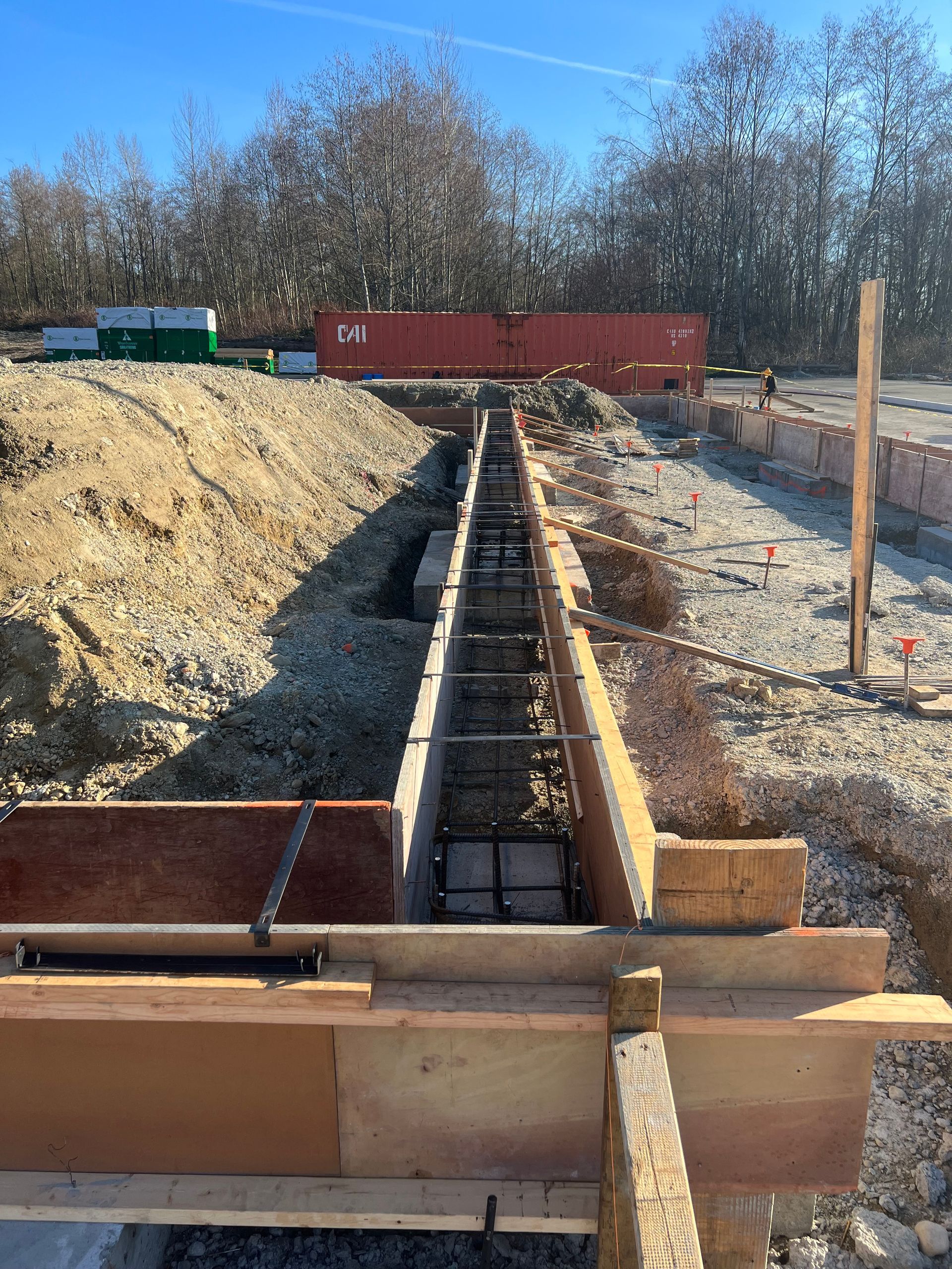 Construction site with a trench. Wooden forms and rebar are in place, awaiting concrete.