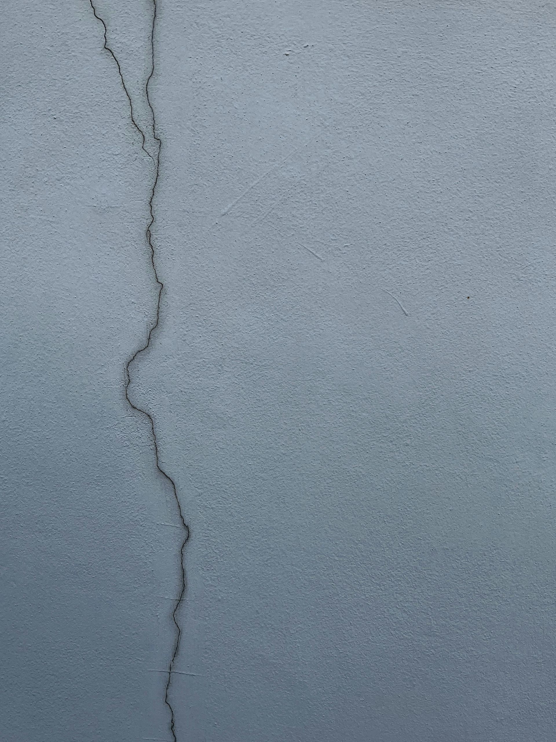A light blue wall with a dark, winding crack running vertically through it.