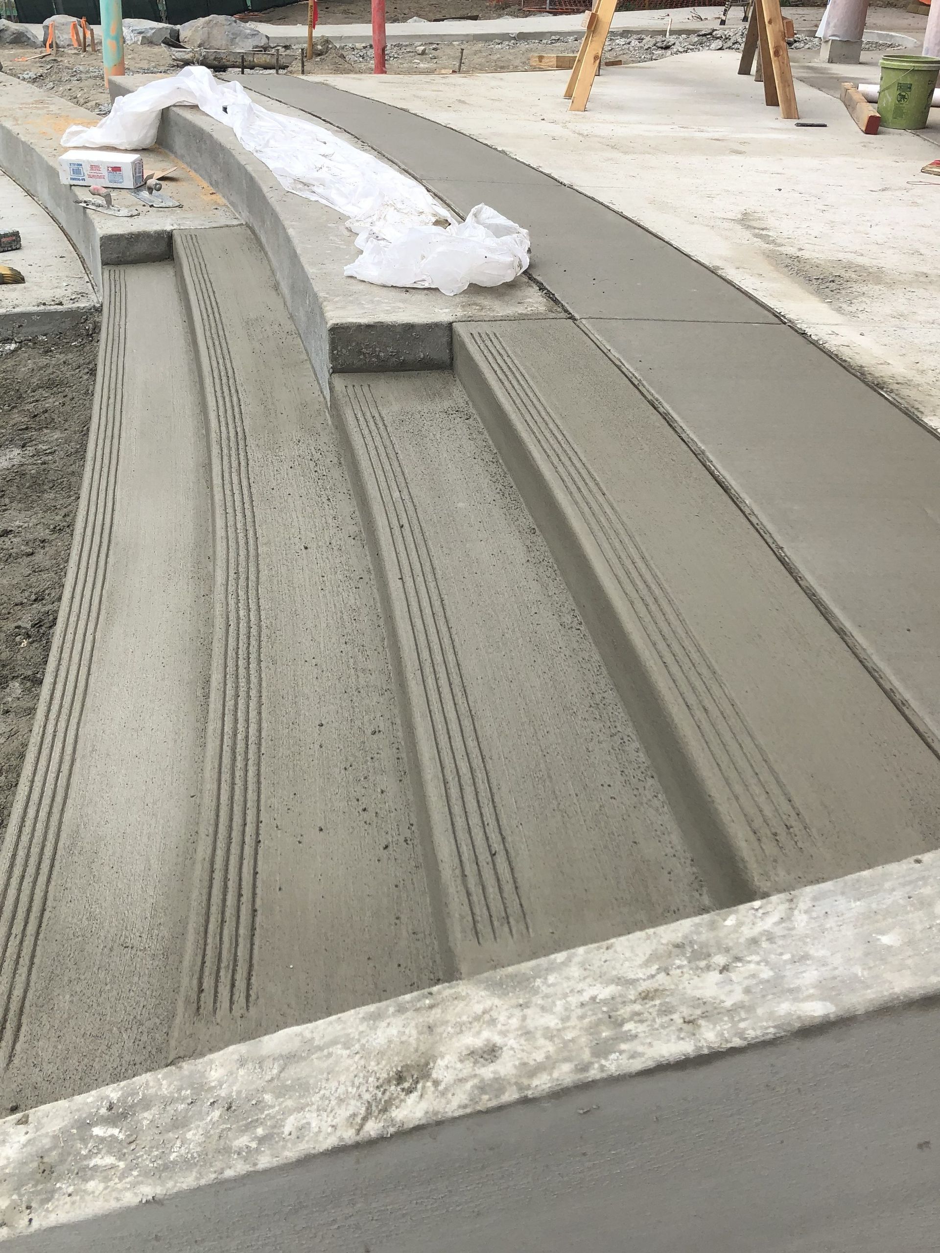 Newly poured concrete steps and walkway under construction; gray with textured grooves.