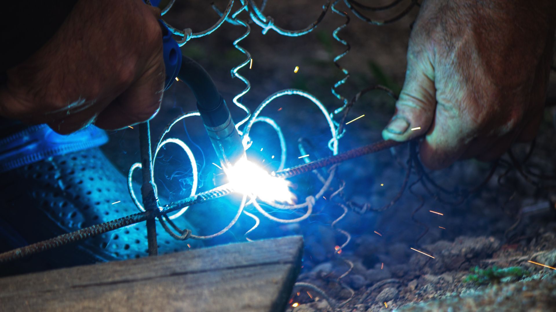 A person is welding a piece of metal with sparks coming out of it