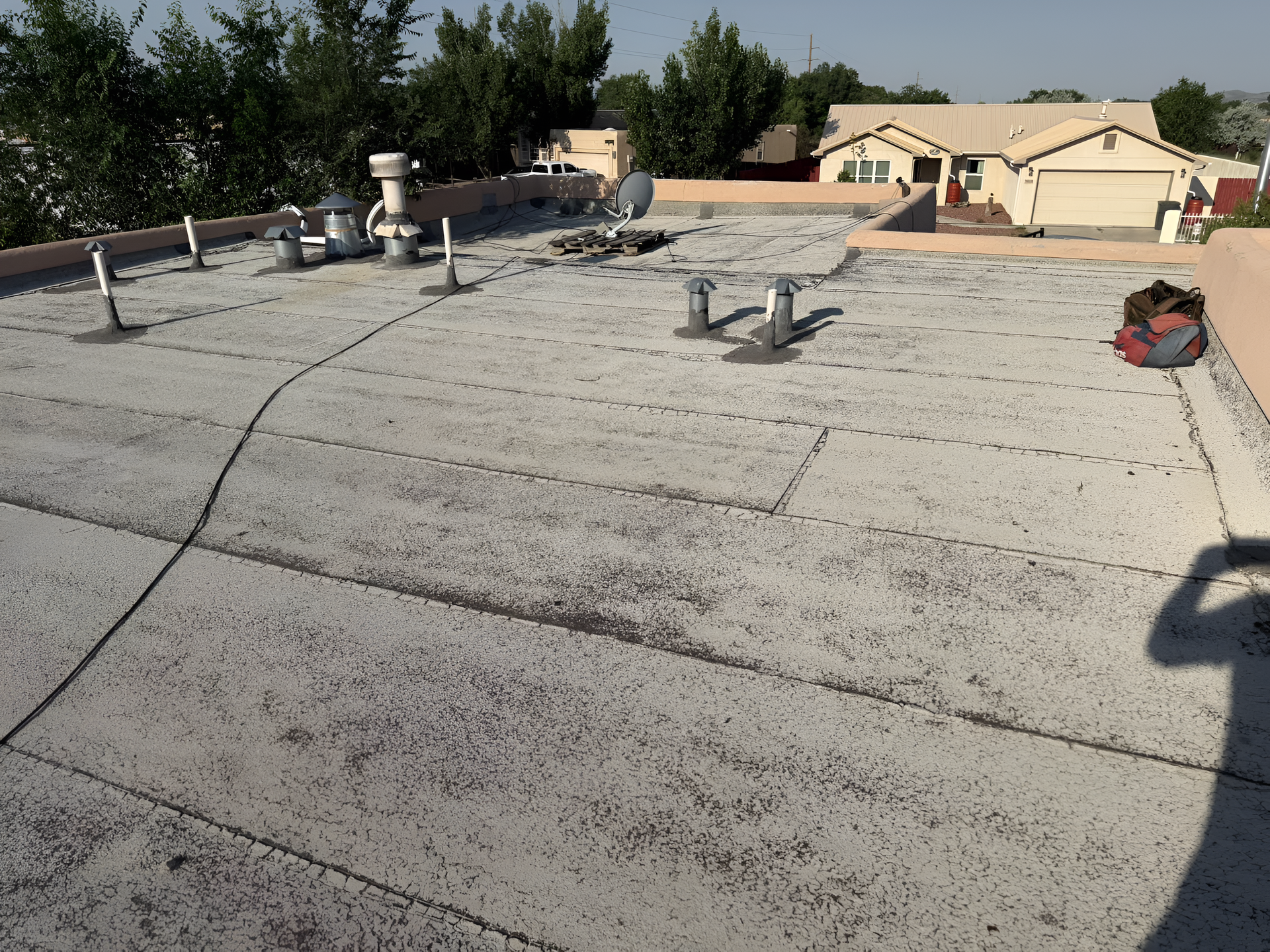 Flat roof with vents, debris, and a shadow of a person.