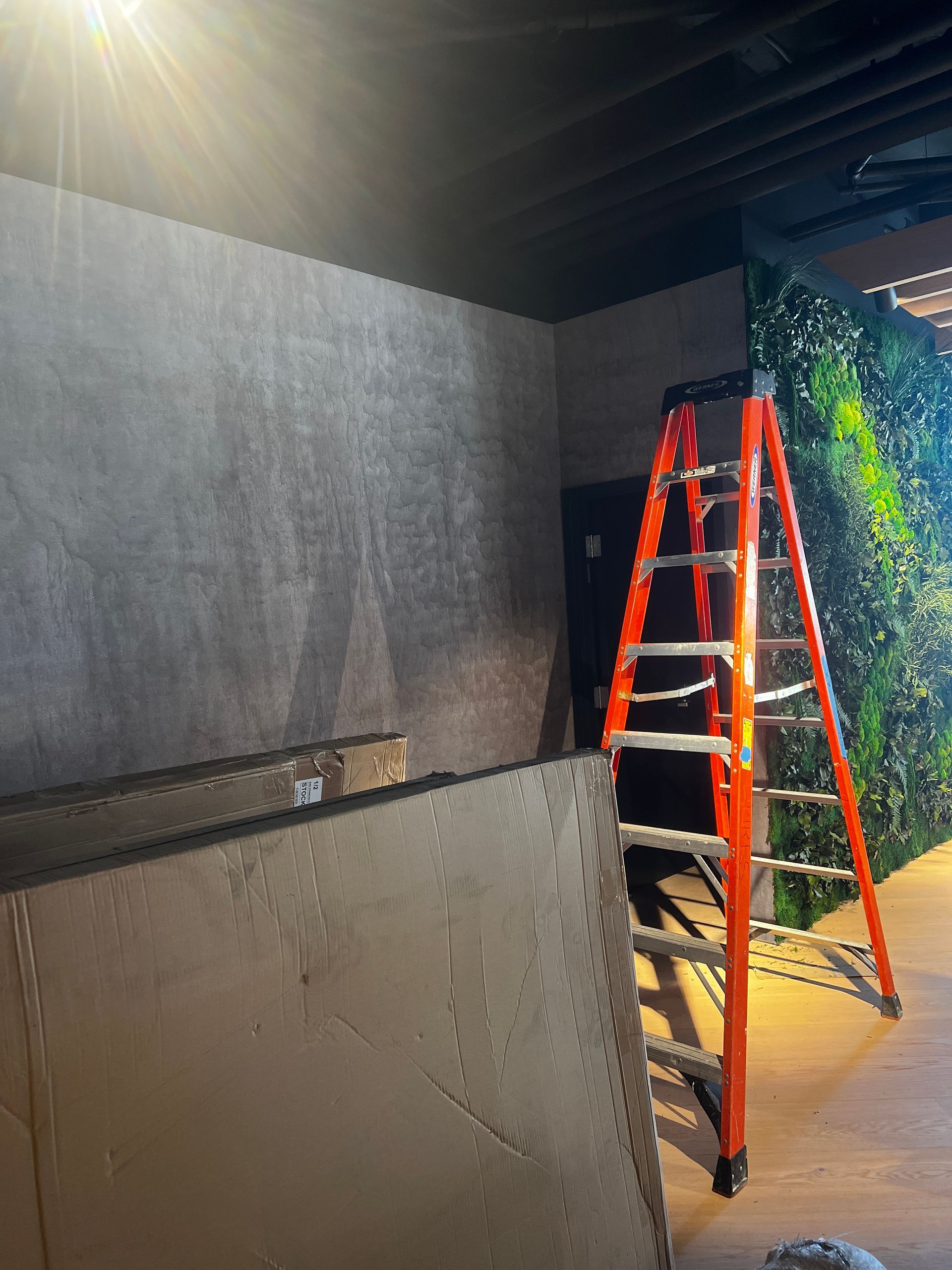 An orange ladder is sitting in a room next to a wall.