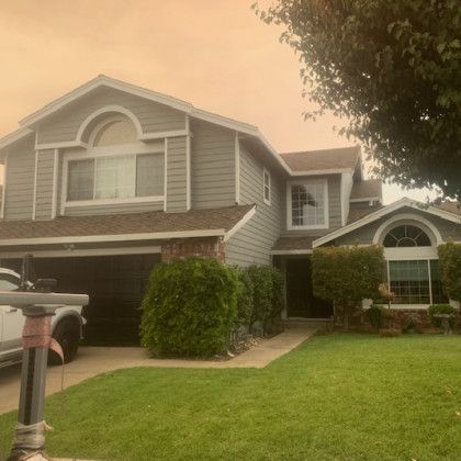A large gray house with a white truck parked in front of it.