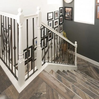 A staircase with a wrought iron railing and a wooden floor.