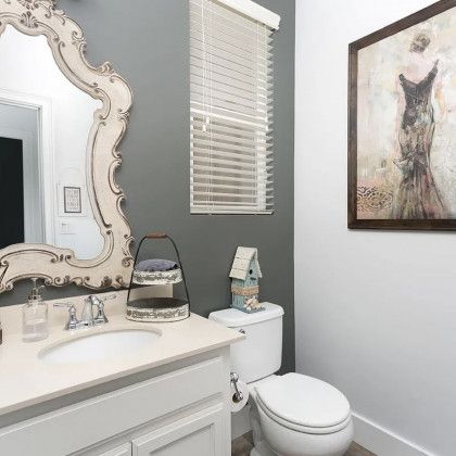A bathroom with a sink , toilet , mirror and picture on the wall.