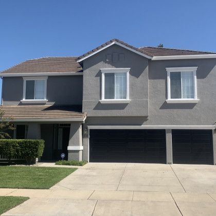 A large gray house with three black garage doors