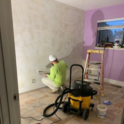 A man is kneeling down in a room with a vacuum cleaner.