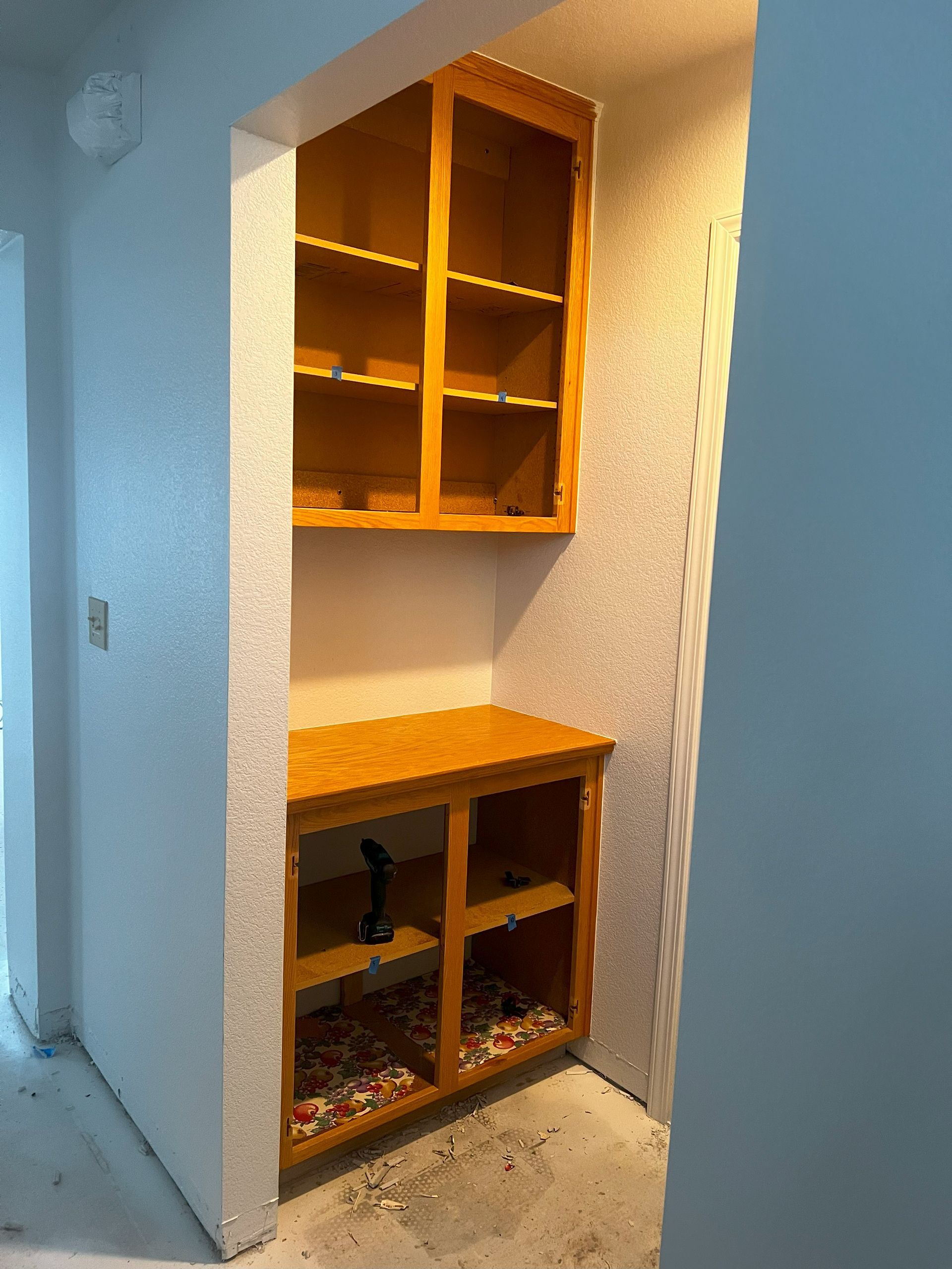 A corner of a room with wooden cabinets and shelves