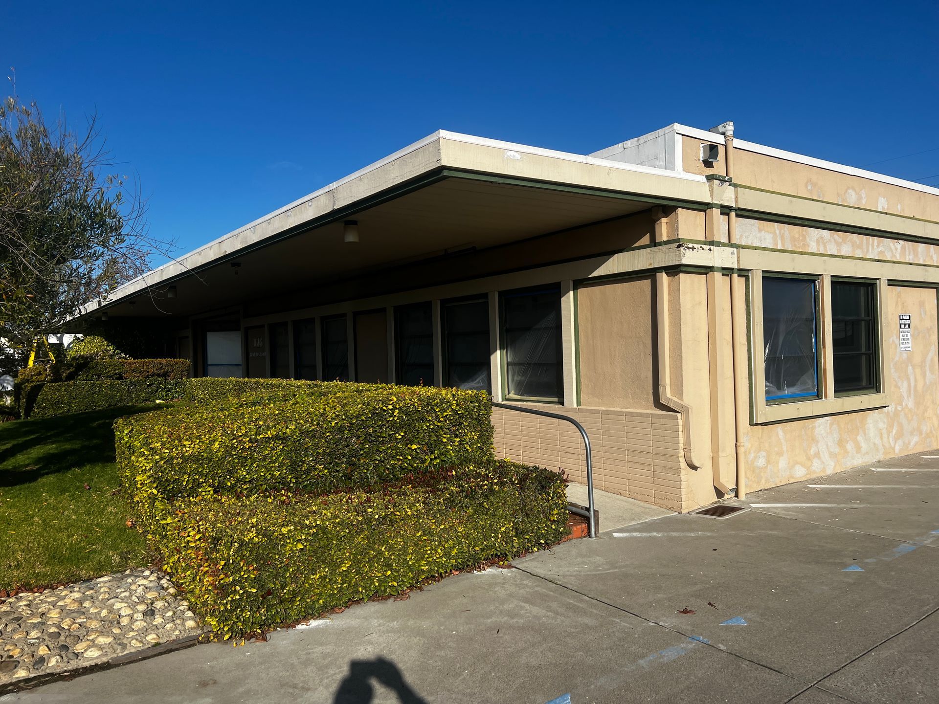 A building with a lot of windows and a shadow on the sidewalk