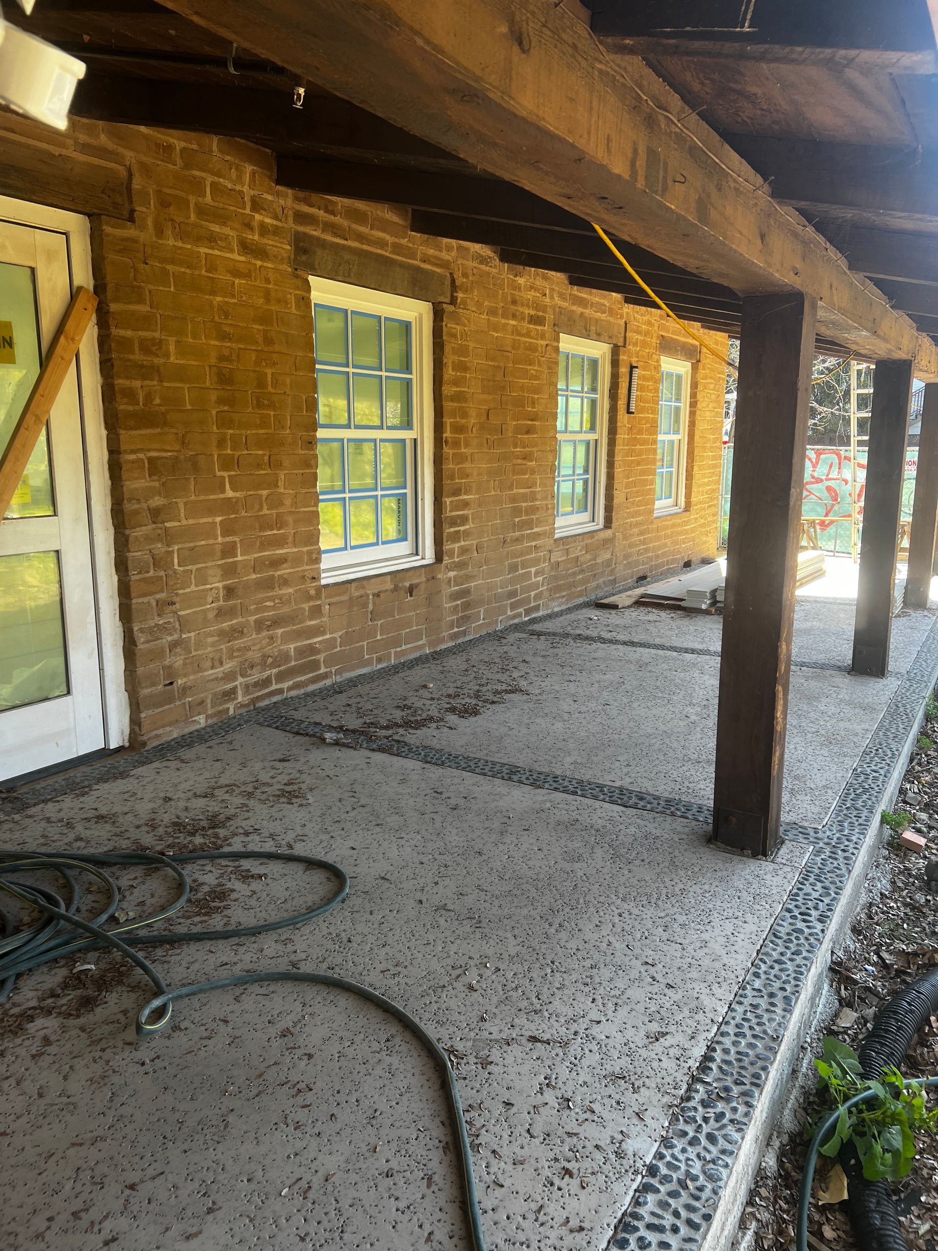 A brick building with a covered porch and a hose in front of it.