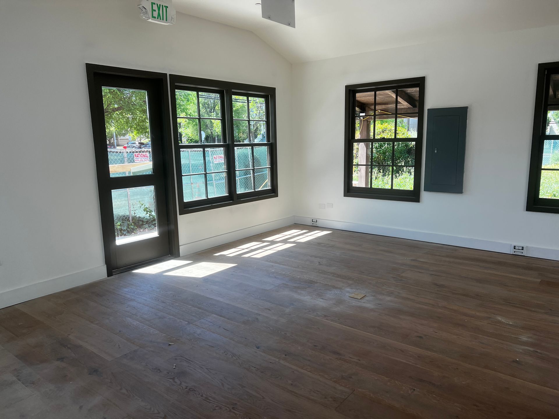 An empty room with a green exit sign on the ceiling