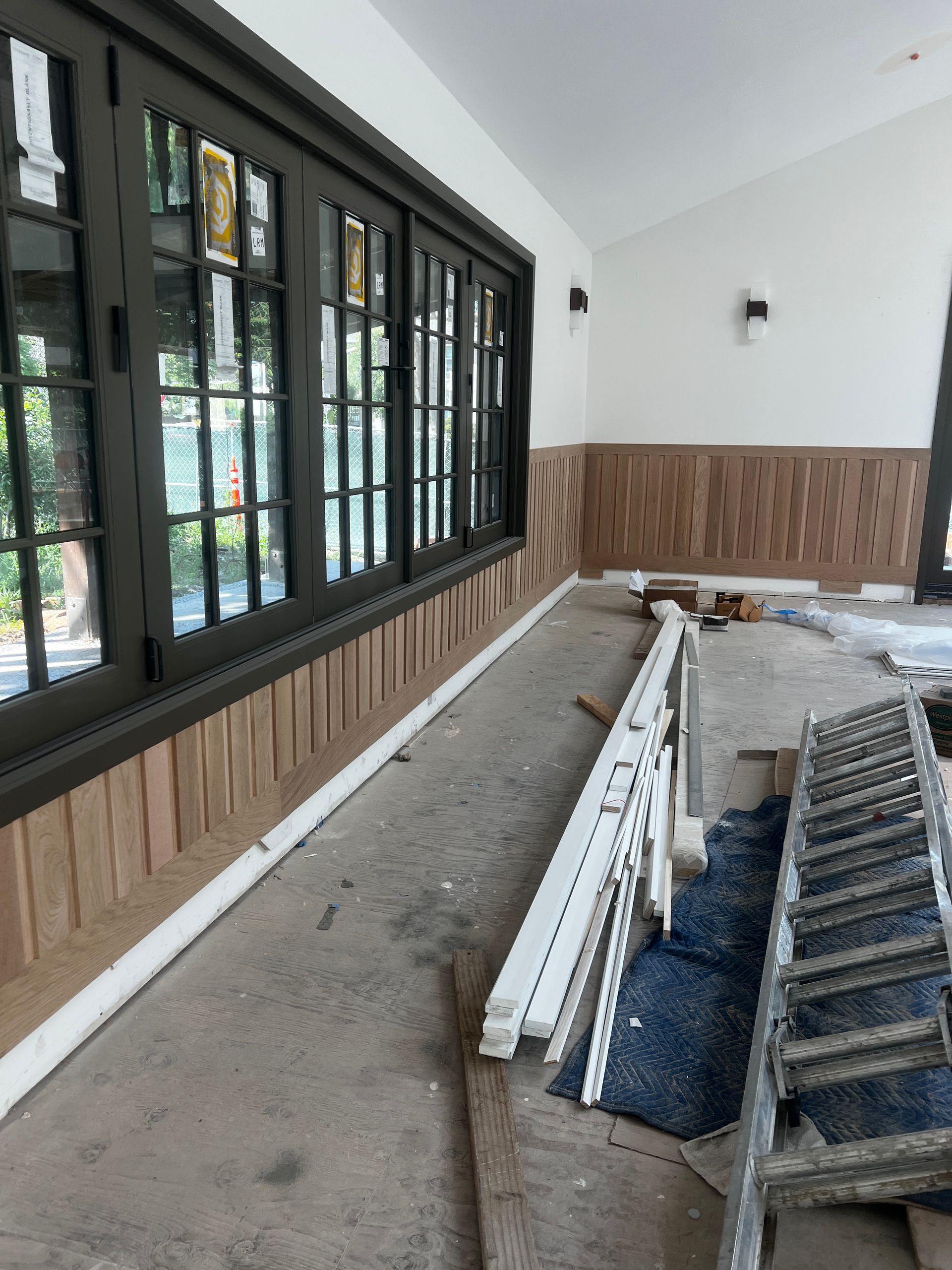 A room with a lot of windows and a ladder on the floor