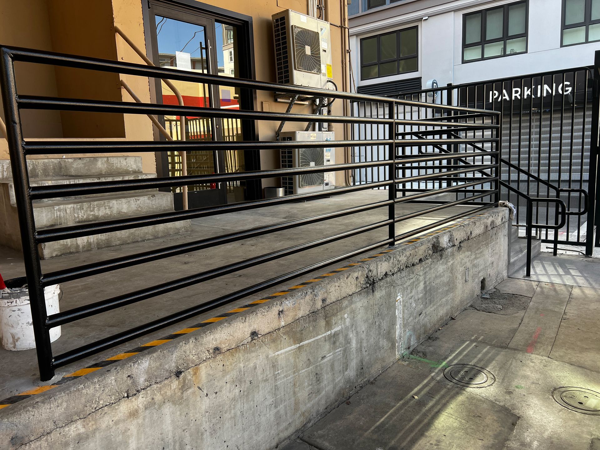 A black railing is surrounding a ramp leading to a building