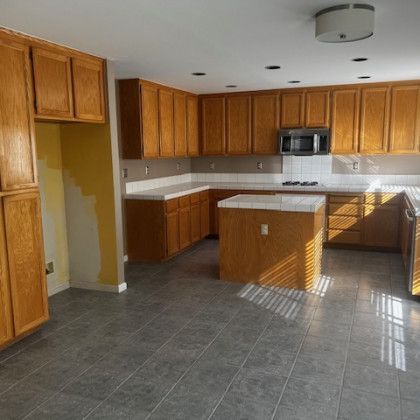 An empty kitchen with wooden cabinets and a tiled floor.