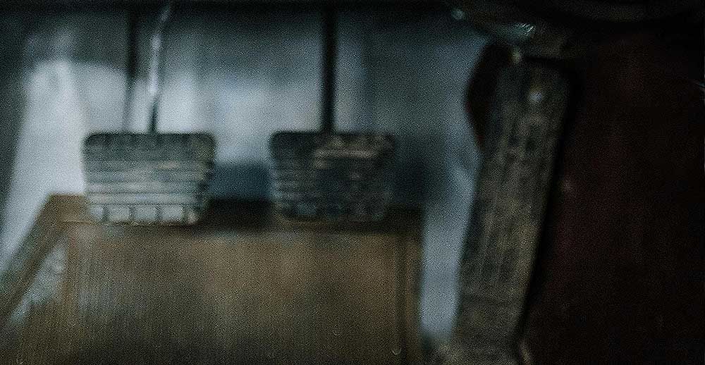 A close up of a car 's brake pedals in a dark room.
