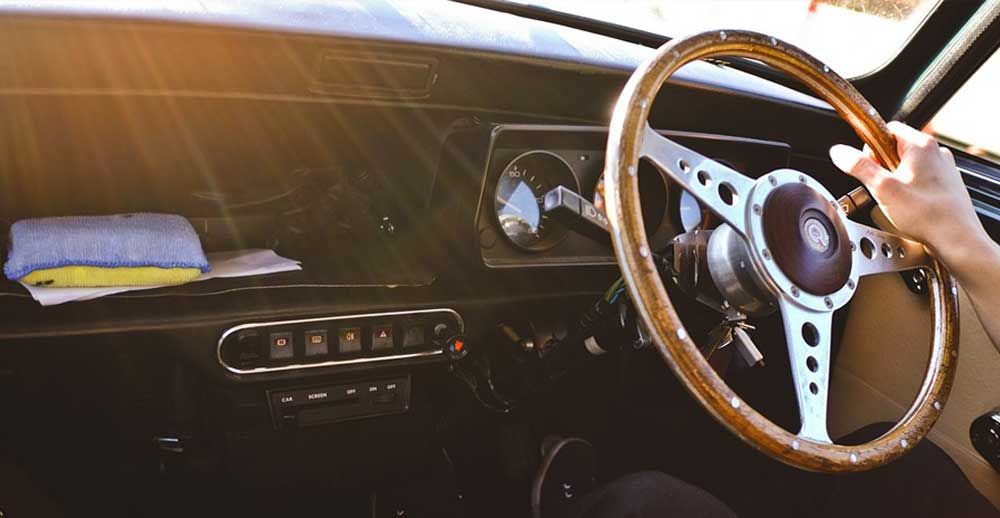 A person is driving a car with a wooden steering wheel.