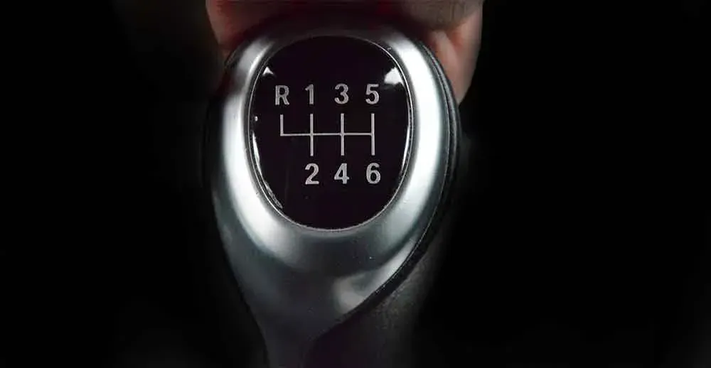 A close up of a person holding a shifter in their hand.
