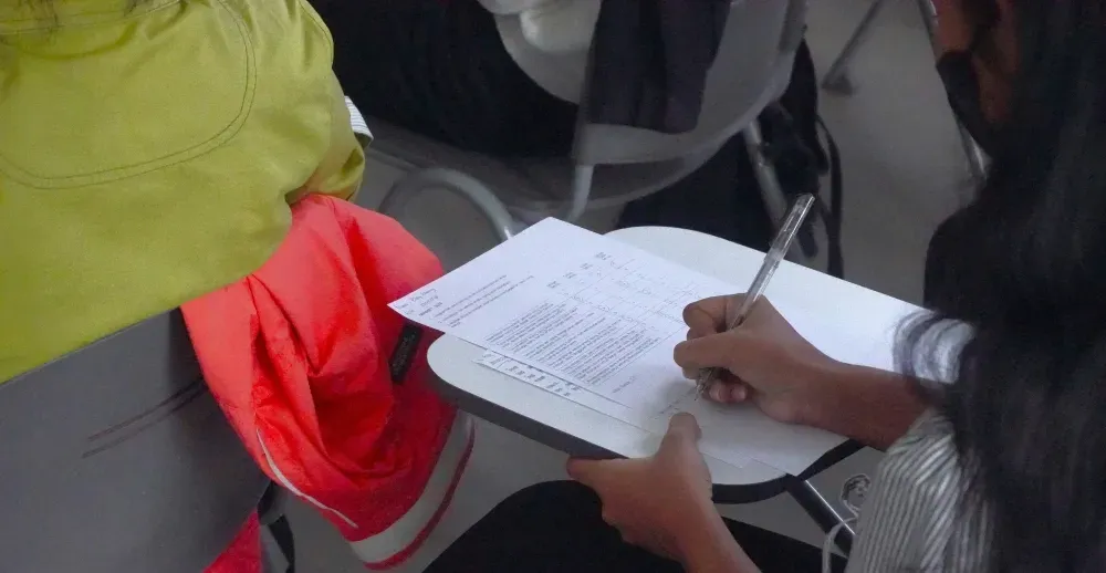 A person is writing on a piece of paper with a pen