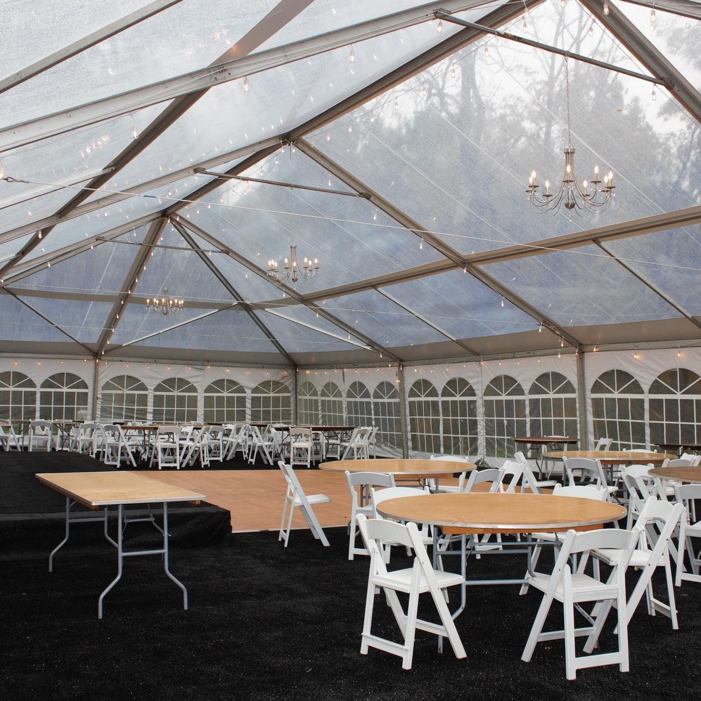 Clear tent interior set up with tables and chairs, ready for an event.