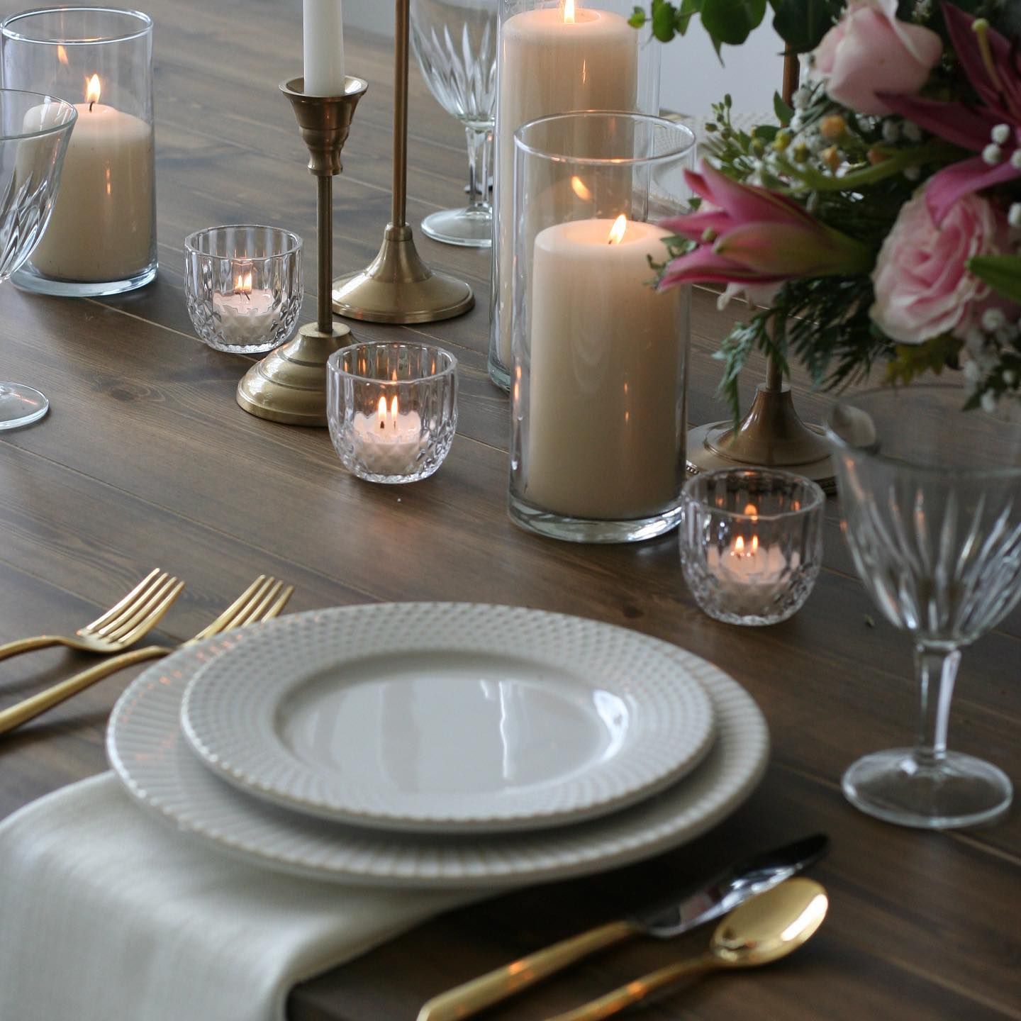 Elegant table setting with candles, floral arrangement, and white plates.
