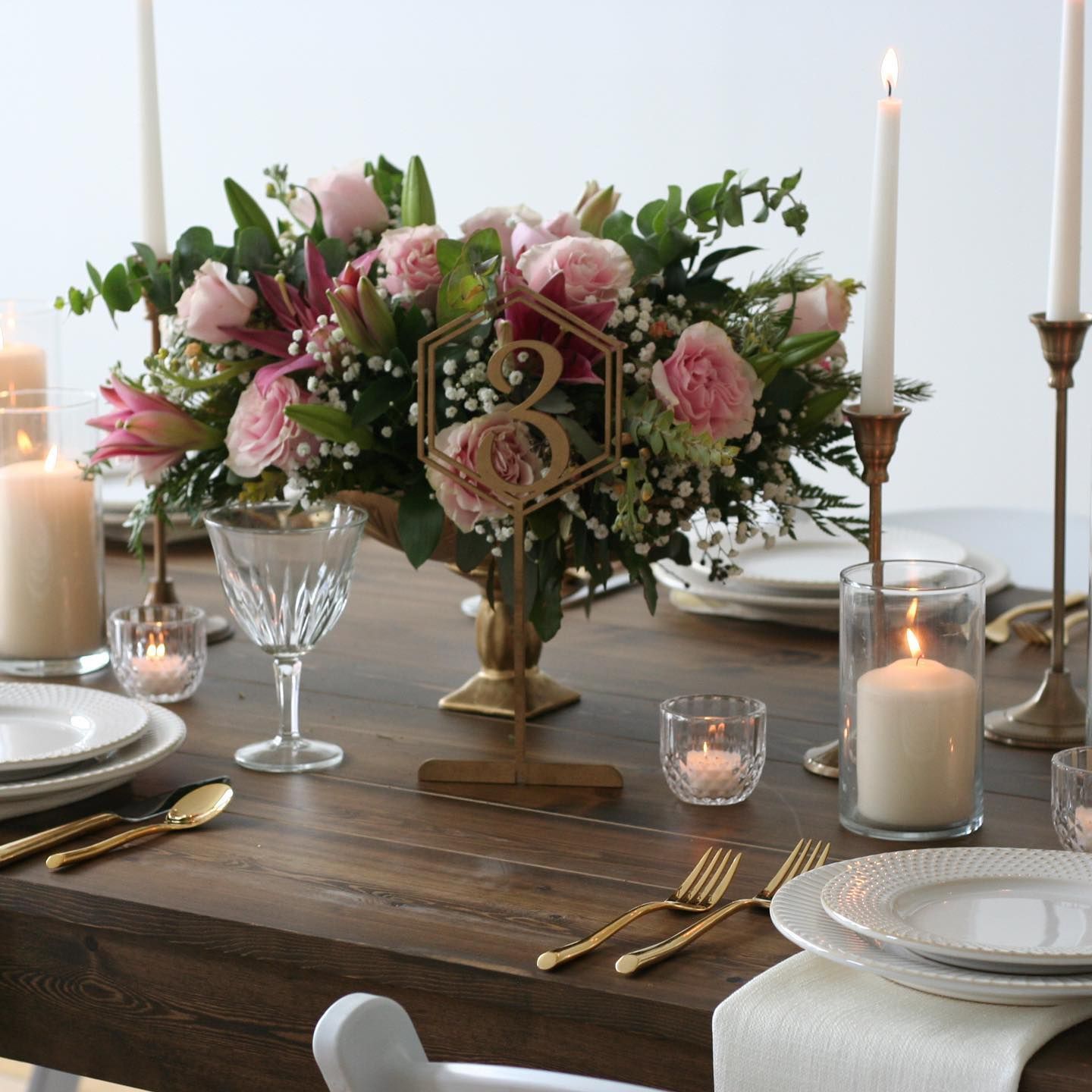Table setting with floral centerpiece, candles, and gold accents.