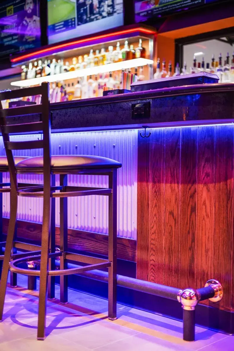 A bar with a lot of bottles on it and a purple light on the bar.