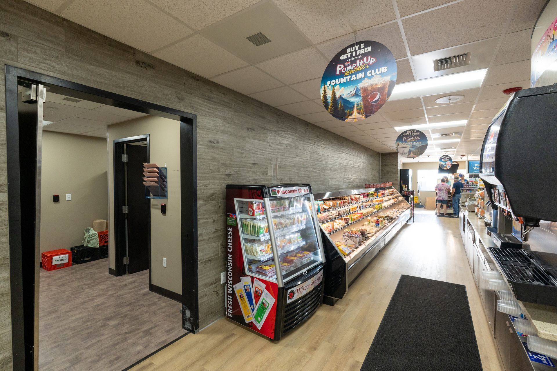 The inside of a grocery store with a refrigerator and a vending machine.