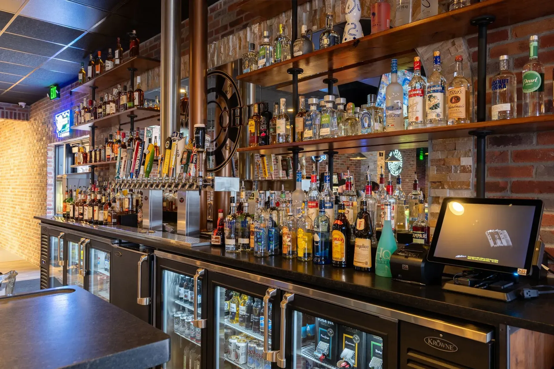 A bar filled with lots of bottles of liquor and a computer monitor.